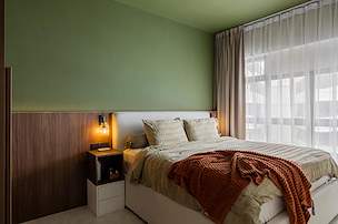 Modern 5-room HDB bedroom in Northshore with green walls, wood paneling and warm bedside lighting