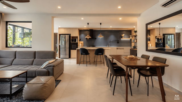225 Kim Keat 225 Kim Keat HDB dining area with a wood dining table, dark kitchen cabinetry and warm pendant lighting